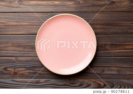 Top view of empty pink plate on wooden background. Empty space for your design Top view of empty pink plate on wooden background. Empty space for your design 90278611