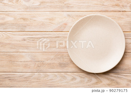 Top view of empty light plate on wooden background. Empty space for your design Top view of empty light plate on wooden background. Empty space for your design 90279175