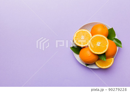 Flat lay of Fresh orange fruit with sliced in plate on Colored background. Top view with copy space Flat lay of Fresh orange fruit with sliced in plate on Colored background. Top view with copy space 90279228