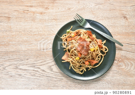 fried spaghetti black pepper sauce topping crispy bacon and corn with green pea on plate 90280891