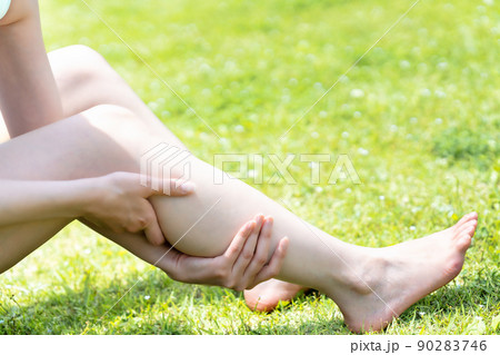 芝生でフットケアする女性の手元【パーツカット】 90283746