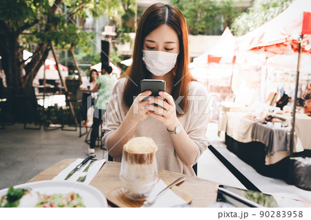 Young adult asian woman wear mask for new normal lifestyle at outdoor restaurant on day 90283958