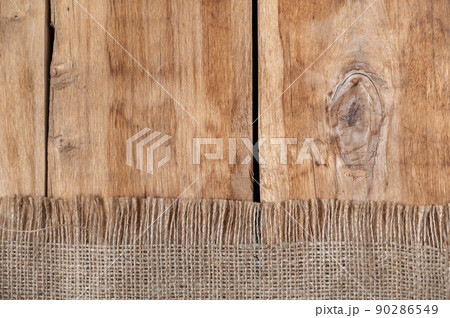 The burlap lies on the tabletop of a wooden table. Rough cloth on top of rough boards. Top view 90286549