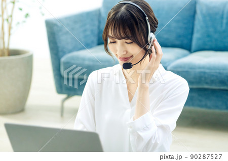 リビングでパソコンを使ってチャットするテレワーク中のオペレーター 90287527