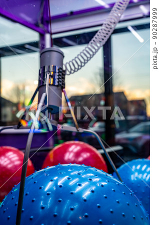 Arcade claw grabber machine with target descending on a toy ball. Seen through smudged glass Arcade claw grabber machine with target descending on a toy ball. Seen through smudged glass 90287999