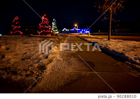 Ice and snow on a sidewalk at night with streetlight reflecting off the slick surface. 90288010
