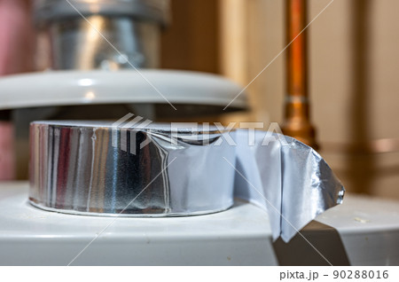 selective focus on the edge of a roll of metallic aluminum foil HVAC duct tape 90288016