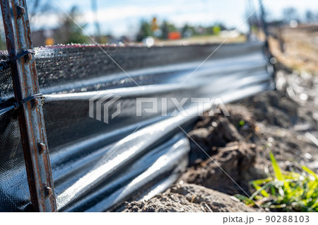 silt fence at a construction site with exposed dirt piled against the fabric 90288103