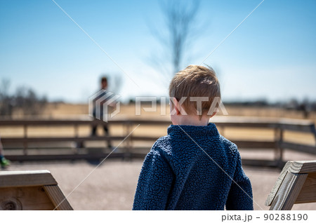 Child waiting along fence for next round of gaga ball in a school playground. Child waiting along fence for next round of gaga ball in a school playground. 90288190