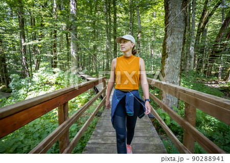 Young woman walking on the bridge on tourist trail in nature park Young woman walking on the bridge on tourist trail in nature park 90288941