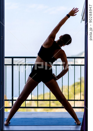 Young woman doing her morning exercise routine at the balcony in the morning. 90288947