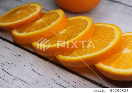 Slices of orange stacked on top of each other on a wooden table.. 90290323