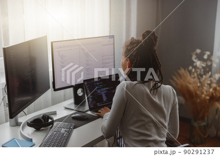 Rear of young woman looking at computer screen while working programming on laptop Rear of young woman looking at computer screen while working programming on laptop 90291237