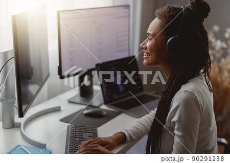Close up shot of positive beautiful female listening to music in headphones browsing on computer 90291238