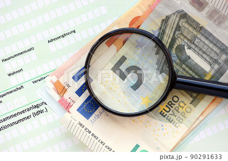German income tax return form with magnifying glass and european euro money bills lies on accountant table close up. Taxpayers in Germany using euro currency to pay taxes 90291633