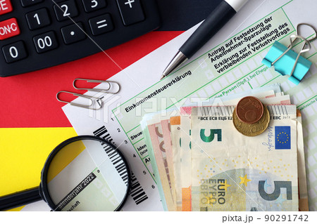 German income tax return form with pen and european euro money bills lies on flag close up. Taxpayers in Germany using euro currency to pay taxes German income tax return form with pen and european euro money bills lies on flag close up. Taxpayers in Germany using euro currency to pay taxes 90291742