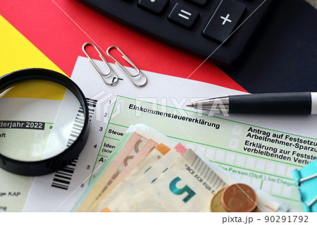 German income tax return form with pen and european euro money bills lies on flag close up. Taxpayers in Germany using euro currency to pay taxes German income tax return form with pen and european euro money bills lies on flag close up. Taxpayers in Germany using euro currency to pay taxes 90291792