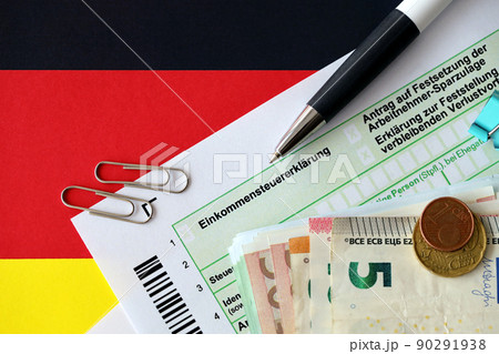 German income tax return form with pen and european euro money bills lies on flag close up. Taxpayers in Germany using euro currency to pay taxes 90291938