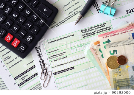 German income tax return form with pen and european euro money bills lies on accountant table close up. Taxpayers in Germany using euro currency to pay taxes 90292000