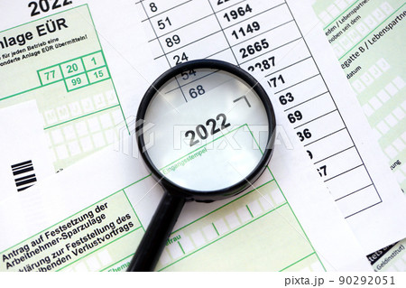 German different tax forms and magnifying glass pointed on 2022 inscription. The concept of taxpaying perion 90292051