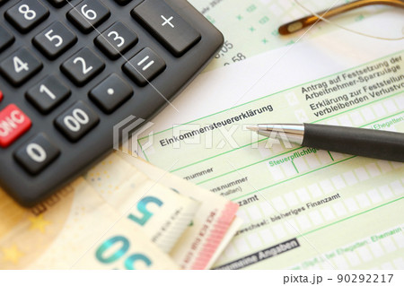 German income tax return form with pen and european euro money bills lies on accountant table close up. Taxpayers in Germany using euro currency to pay taxes German income tax return form with pen and european euro money bills lies on accountant table close up. Taxpayers in Germany using euro currency to pay taxes 90292217
