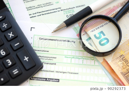 German income tax return form with pen and european euro money bills lies on accountant table close up. Taxpayers in Germany using euro currency to pay taxes German income tax return form with pen and european euro money bills lies on accountant table close up. Taxpayers in Germany using euro currency to pay taxes 90292373