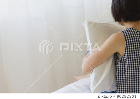 ベッドに座って枕を抱える女性2 90292501