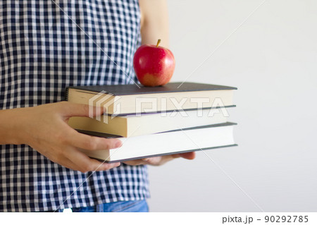 本とリンゴを持った女性の上半身 90292785