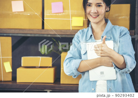 Asian woman startup small business at home office. Online seller entrepreneur young asian woman use tablet checking online order. Woman using tablet check stock goods supply delivery package shipping 90293402