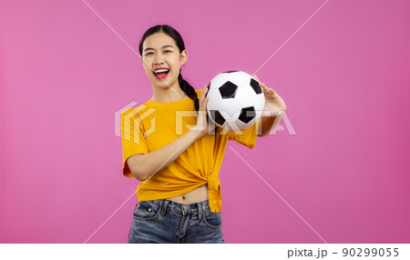Happy Asian Girl football fan over isolated pink background holding a soccer ball and looking at camera, sport and people concept Happy Asian Girl football fan over isolated pink background holding a soccer ball and looking at camera, sport and people concept 90299055