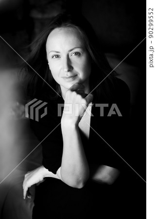 Black and white photo of an attractive woman. A large portrait on a dark background. Vertical photo. 90299552