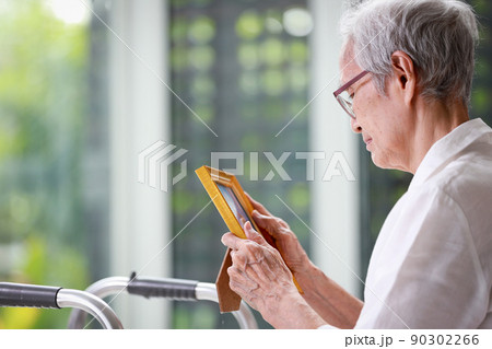 Sad old elderly with depression looks at photograph of her family with nostalgia,remembrance,Depressed asian senior woman patient holding picture frame,sitting alone in loneliness at nursing home 90302266