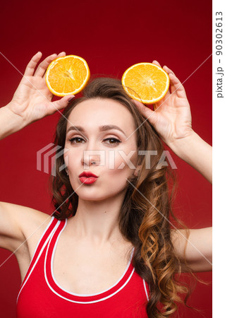 A beautiful woman in a red swimsuit with oranges 90302613
