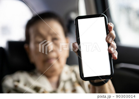Asian old woman age 80 - 90 years old showing a blank screen smartphone, isolated with clipping path. Modern Asian grandmother concept with connectivity and internet technology. Empty white screen. 90303014