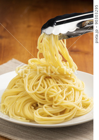 トングを使ってパスタをお皿に取り分けます トングを使ってパスタをお皿に取り分けます 90303295