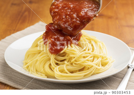 ソースレードルでパスタにミートソースをかけて食事の準備をしています ソースレードルでパスタにミートソースをかけて食事の準備をしています 90303453