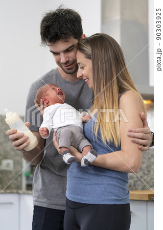 mother and father bottle feeding their newborn baby in the kitchen mother and father bottle feeding their newborn baby in the kitchen 90303925