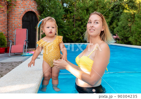 Summer vacation. Young caucasian mother and her little cute daughter relax in a pool and refreshing. Learning swimming 90304235