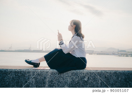 制服姿の女子高生と綺麗な夕焼けの空 90305107