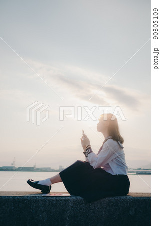 制服姿の女子高生と綺麗な夕焼けの空 90305109