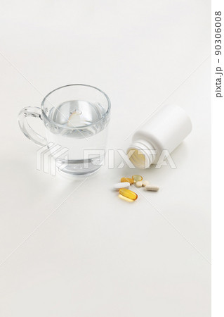 a cup of water and a pills, white background, medical creative concept photo a cup of water and a pills, white background, medical creative concept photo 90306008