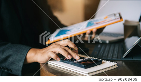 Businessman are calculating on calculator with financial data and report graph at home office. Businessman are calculating on calculator with financial data and report graph at home office. 90308409