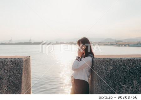 制服姿の女子高生と美しい夕焼け空 90308766