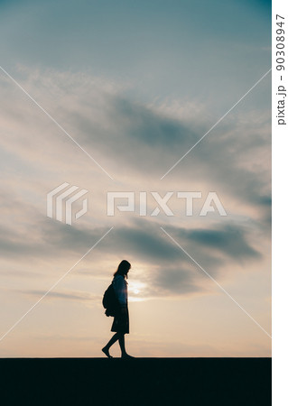 制服姿の女子高生と美しい夕焼け空 90308947