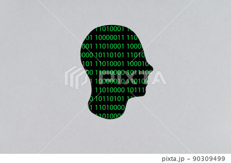 Silhouette of a human cardboard head cutout with a binary code made up of a set of green digits on a black background in its head 90309499