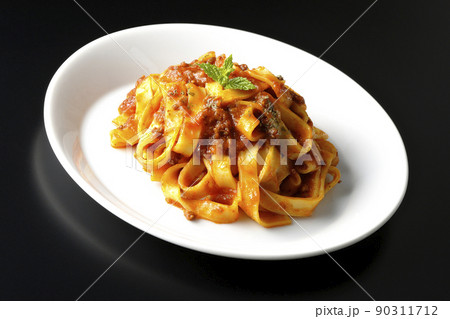 平打ちパスタのフィットチーネとトマトソースがよく絡んだボロネーゼを黒背景で撮影 90311712