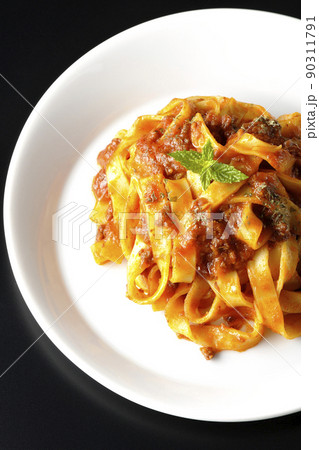 平打ちパスタのフィットチーネとトマトソースがよく絡んだボロネーゼを黒背景で俯瞰撮影 90311791