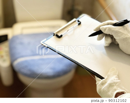トイレを査定するクリップボードを持った白手袋の手元 90312102