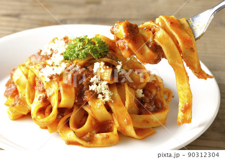 平打ちパスタのフィットチーネとトマトソースがよく絡んだボロネーゼにパルメザンチーズがけを食べる 90312304