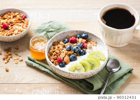 Granola bowl with greek yogurt, blueberries and kiwi Granola bowl with greek yogurt, blueberries and kiwi 90312431